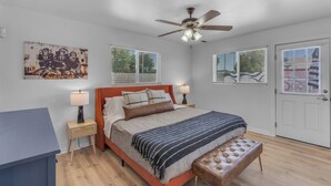 A bedroom with a bed, bedside tables, a ceiling fan, and a door. - Splash Pad - Toys - Pets OK - 8 Min to Oldtown (Scottsdale)