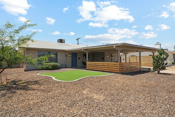 A modern house with a covered patio, a small lawn, and a cactus plant.