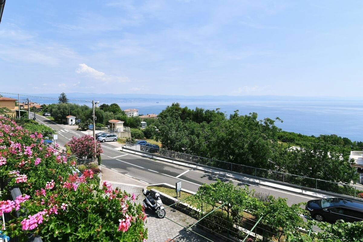 Una strada costiera con vista libera sul mare, immersa nel verde e con edifici residenziali.