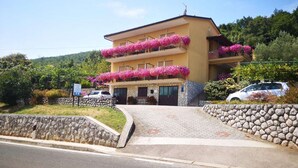 A two-story building with a stone facade and balconies adorned with pink flowers. - Scenic Retreat Rooms and Family Apartment (Moscenicka Draga)