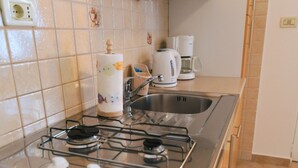 A kitchen with a gas stove, a sink, and a coffee maker. - Scenic Retreat Rooms and Family Apartment (Moscenicka Draga)
