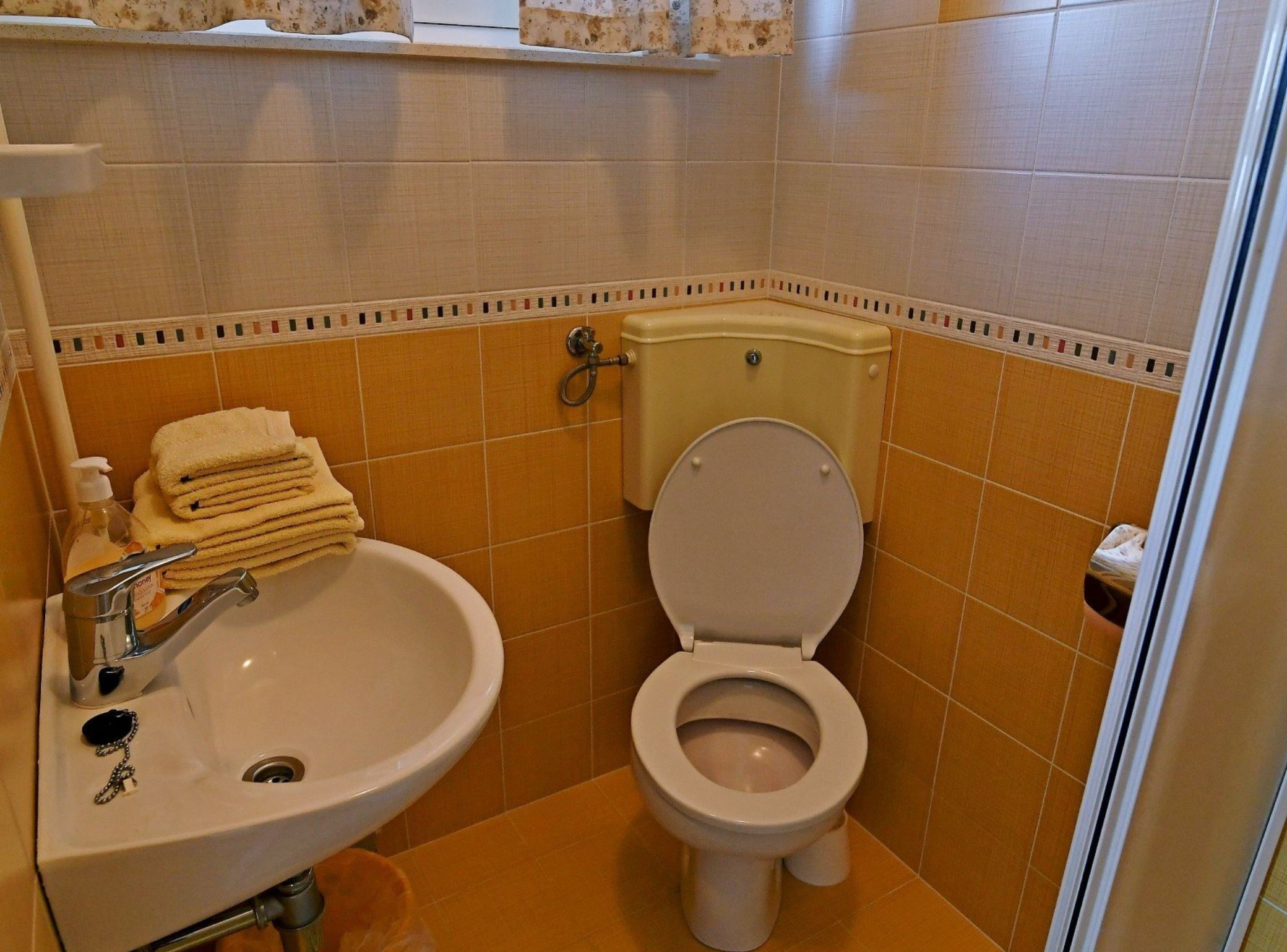 A bathroom with a sink, toilet, and a towel stack.