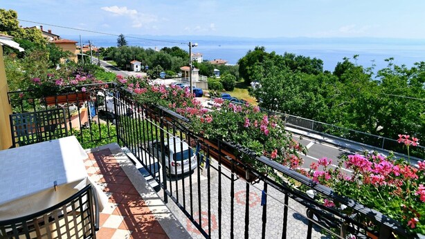 A balcony with a view of the sea, a tiled floor, and a table with a newspaper. - Scenic Retreat Rooms and Family Apartment (Moscenicka Draga)