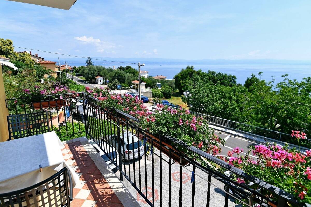 Un balcone con vista sul mare, un pavimento piastrellato e un tavolo con un giornale.