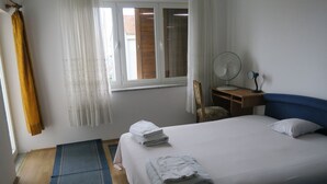 A bedroom with a bed, a chair, a desk with a lamp, and a window with curtains. - Cozy Lovran Apartment With Balcony (Lovran)