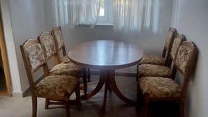 A dining area with a round wooden table surrounded by six floral-patterned chairs. - Cozy Lovran Apartment With Balcony (Lovran)