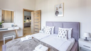 Quarto de hotel moderno com uma cama, mesas de cabeceira, uma escrivaninha e um banheiro visível por uma porta aberta.