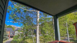 A porch with a view of a mountain, trees, and a pathway leading to a building. - Telluride Lodge, Your mountain gateaway with amazing service and very affordable (Telluride)