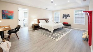 Une chambre à coucher comprenant un lit, des tables de chevet, un bureau, une chaise, un ventilateur de plafond et une fenêtre.