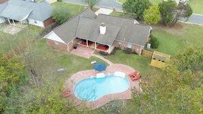 Ein Luftbild eines Hauses mit Schwimmbad, überdachter Terrasse und umzäunter Garten.
