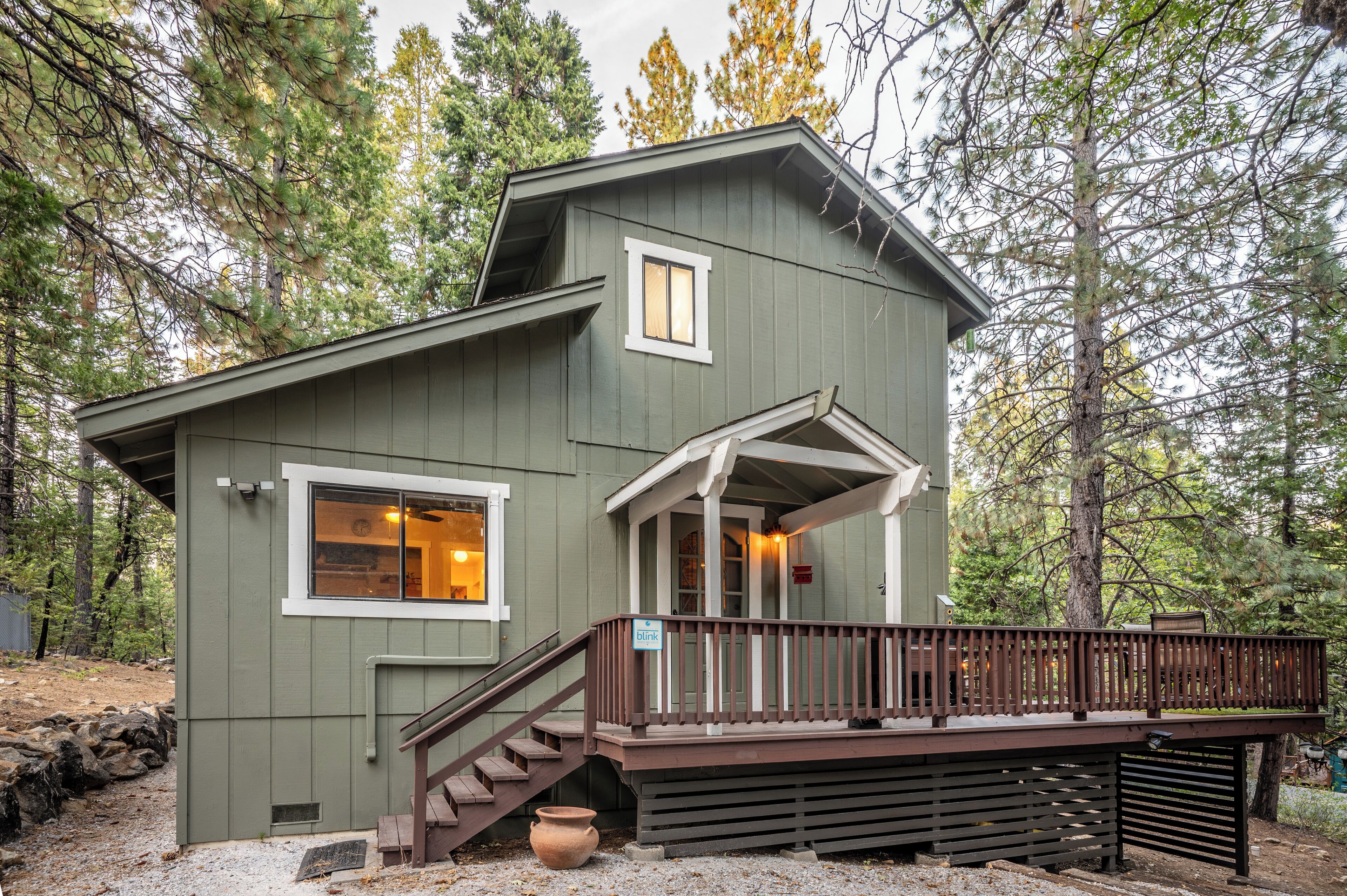 A cabin with a wooden deck, a front porch, and a staircase leading to the entrance.