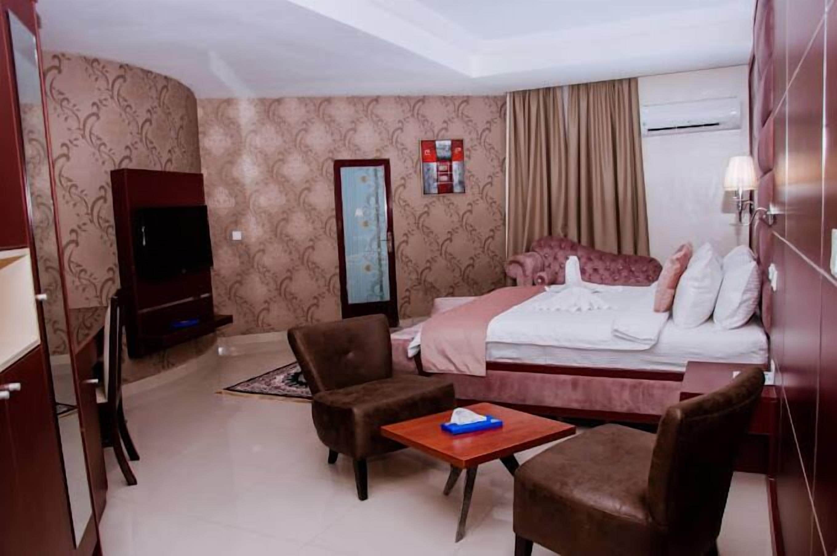 Una habitación de hotel con cama, televisor, escritorio y dos sillas.