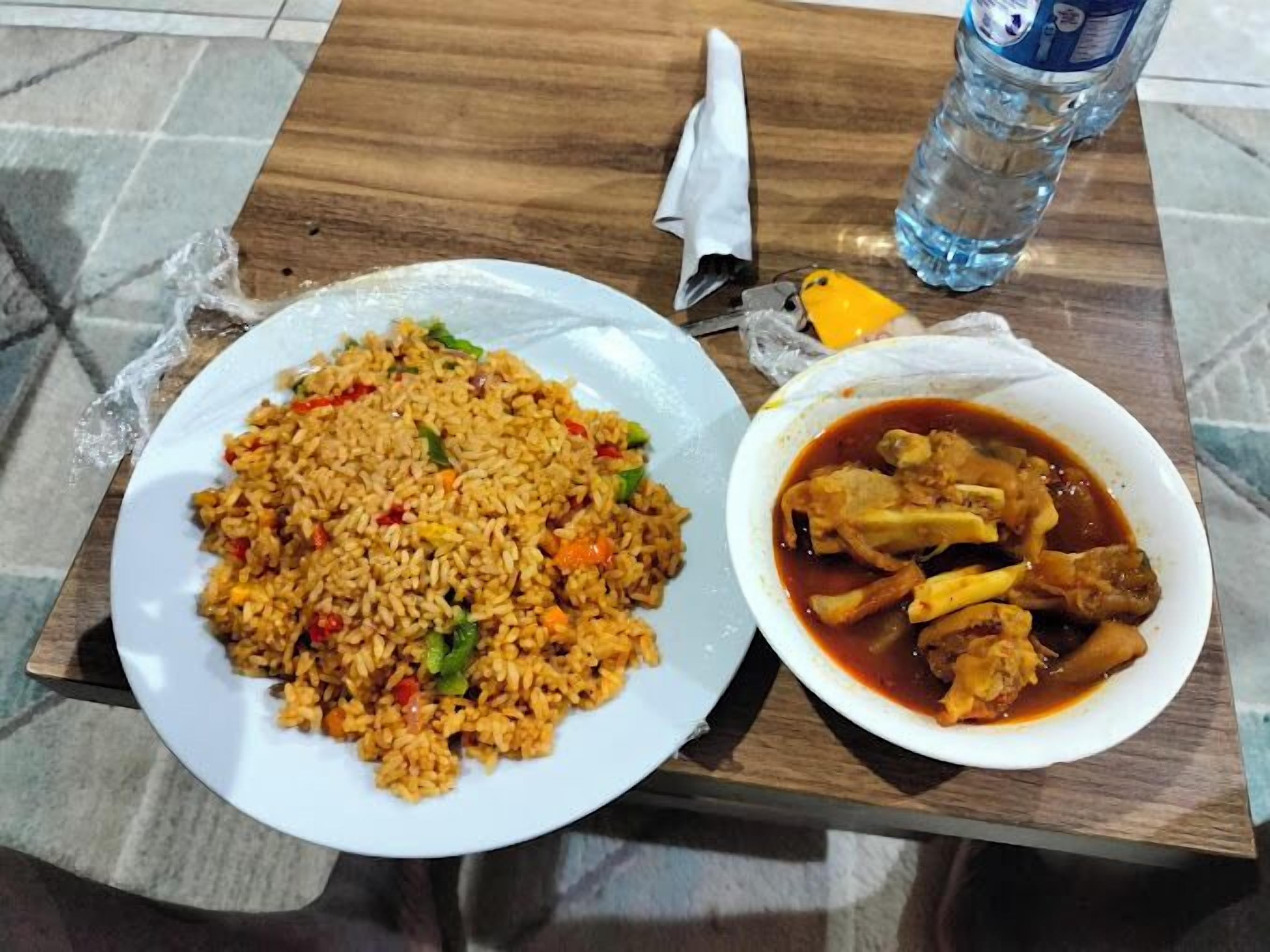 A plate of fried rice with vegetables and a bowl of chicken stew.