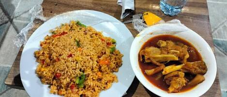 A plate of fried rice with vegetables and a bowl of chicken stew.