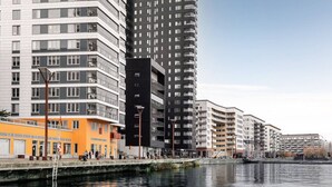 A waterfront urban area with modern high-rise buildings, a canal, and a pedestrian walkway. - Stylish Waterfront Apt Stockholm (Stockholms län)