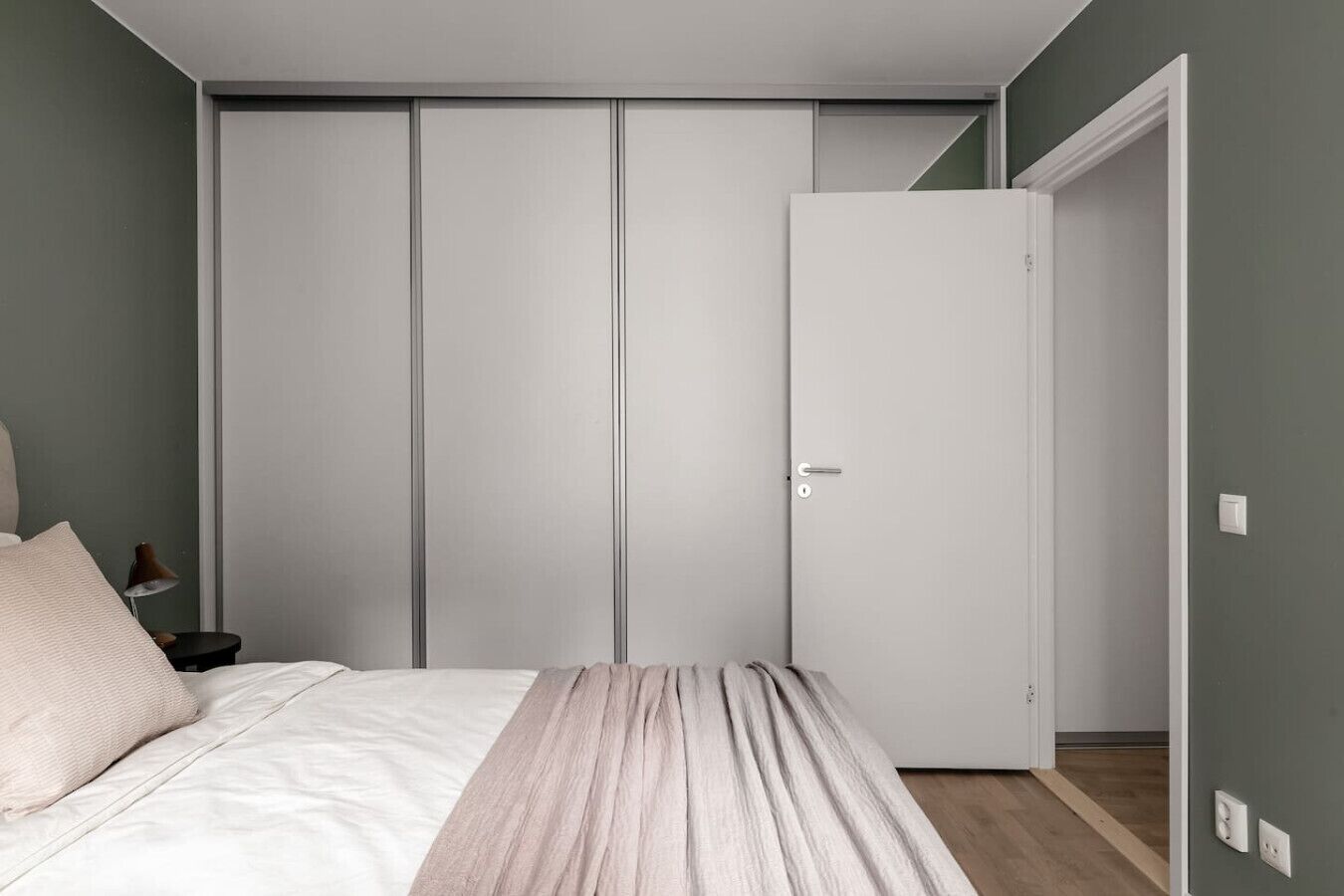 Une chambre à coucher comprenant un lit, une table de chevet, une armoire et une porte donnant sur une autre pièce.