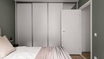 Une chambre à coucher comprenant un lit, une table de chevet, une armoire et une porte donnant sur une autre pièce.