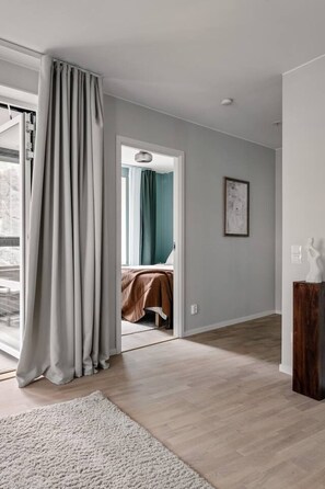 A modern room with a large window, a bed with a brown cover, a wooden floor, and a white rug. - Stylish Waterfront Apt Stockholm (Stockholms län)