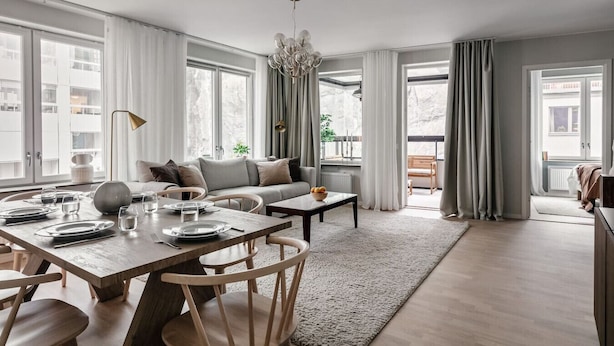 A modern living room with a dining area, large windows, and a view of the outside. - Stylish Waterfront Apt Stockholm (Stockholms län)
