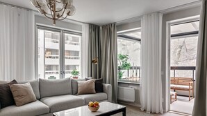 A modern living room with a sofa, coffee table, and a view of a balcony with outdoor furniture. - Stylish Waterfront Apt Stockholm (Stockholms län)