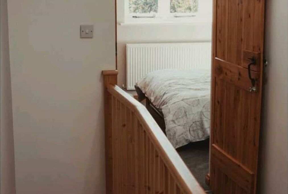 Uma escada de madeira estreita que leva a um quarto com uma cama e um radiador.