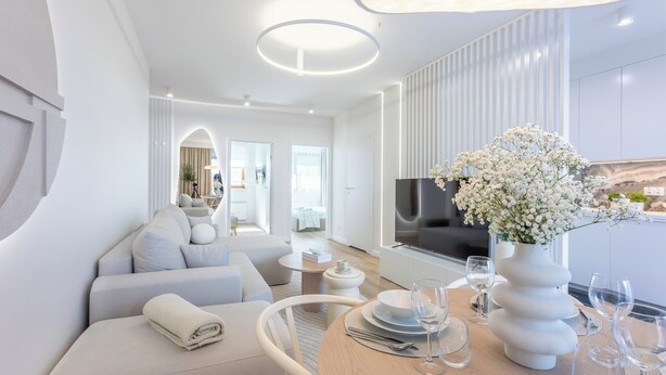 A modern, well-lit living room with a sofa, a dining table set for two, and a large TV. - Vacation apartment by the sea, vacation on the island of Usedom, Apartment White Space II (Swinoujscie)