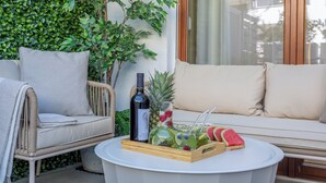 A cozy outdoor seating area with a wicker sofa, a round table with a drink tray, and lush greenery in the background. - Vacation apartment by the sea, vacation on the island of Usedom, Apartment White Space II (Swinoujscie)