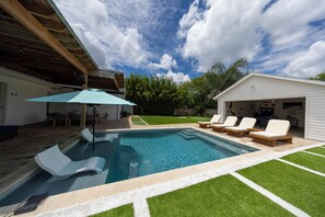 A swimming pool with lounge chairs and a covered patio area.