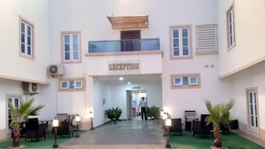 A reception area with a sign, a covered walkway, and outdoor seating. - Porto Golf Hotels (Kano)