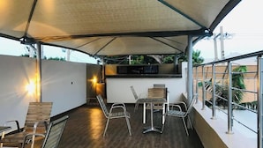 An outdoor patio area with a table and chairs, a built-in grill, and a view of the surrounding area. - Porto Golf Hotels (Kano)