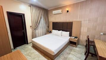 Une chambre d’hôtel avec un grand lit, une table de chevet, un bureau et une chaise.