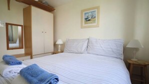 Une chambre d’hôtel avec un lit, une armoire, une table de chevet avec une lampe et un tableau encadré au mur.