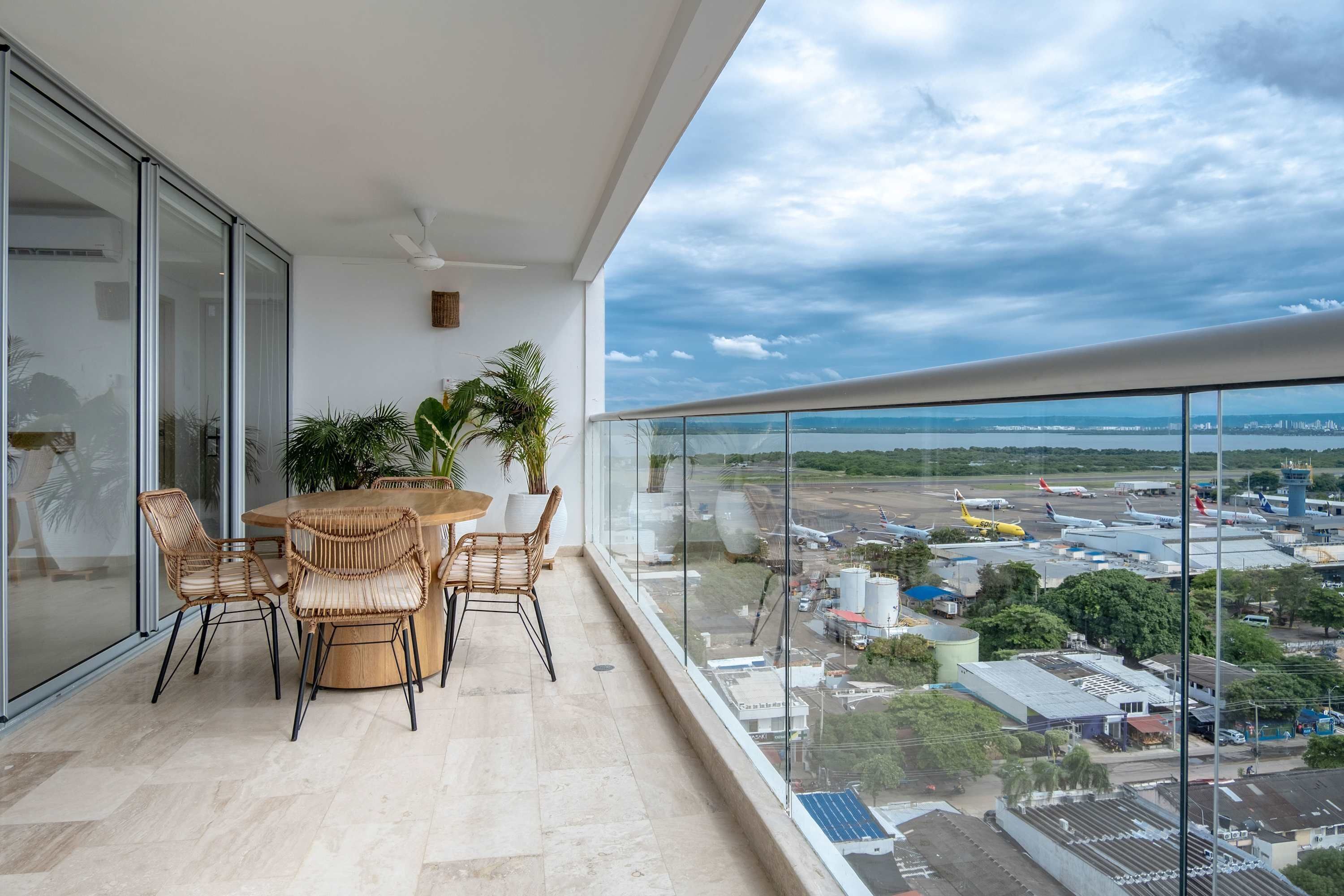 Un balcon avec une table et des chaises, une plante en pot et une vue sur un aéroport.