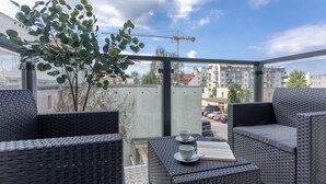 A balcony with wicker furniture, a potted plant, and a view of a construction site.