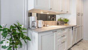 A modern kitchen with white cabinetry, a built-in oven, and a coffee maker.