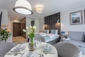 Een moderne hotelkamer met een zithoek, een bed met uitzicht en een tafeltje met een bloevas.