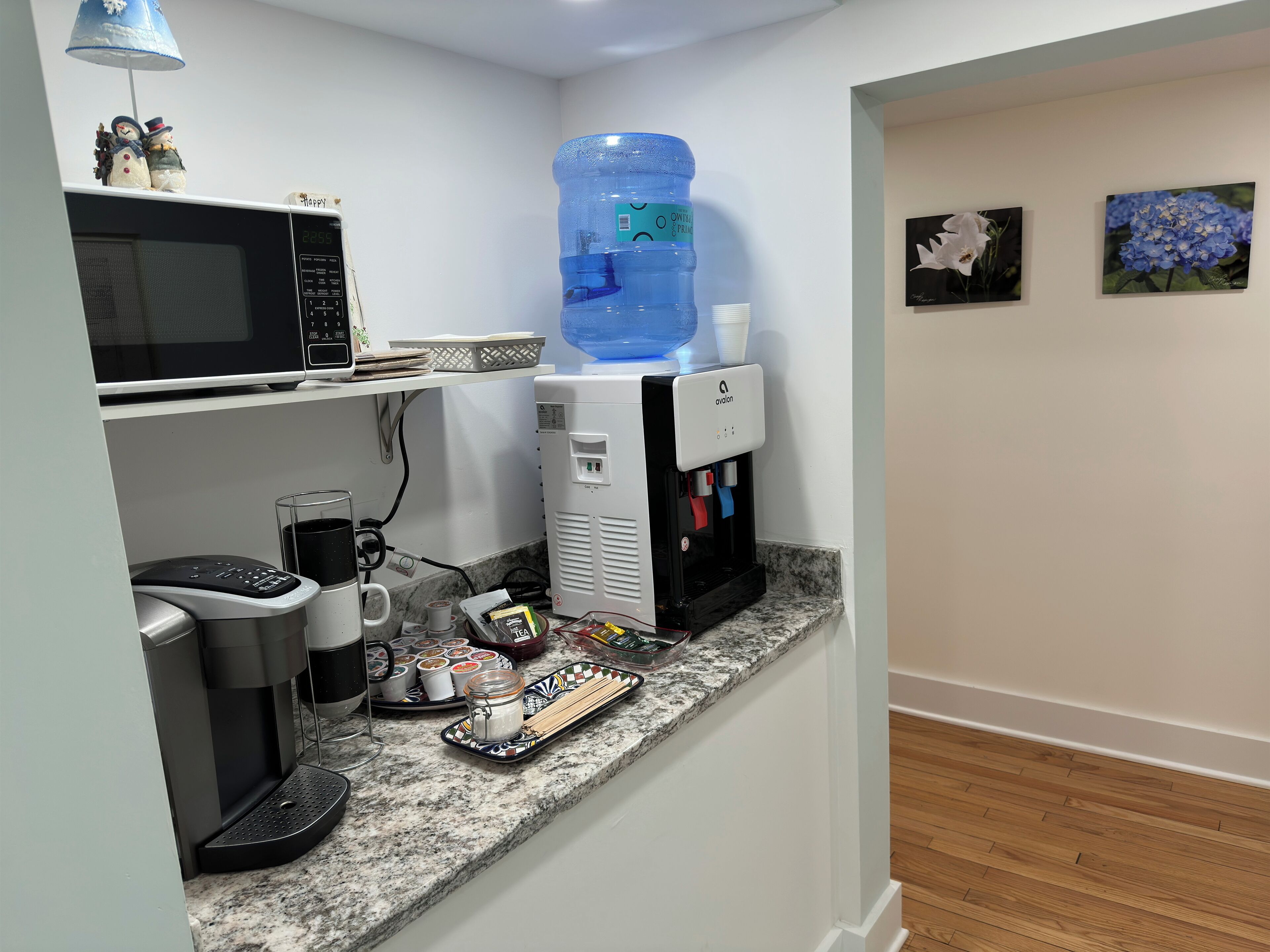 Una kitchenette con microondas, cafetera y dispensador de agua.