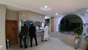 A reception area with a counter, a staircase, and a balcony with a railing.