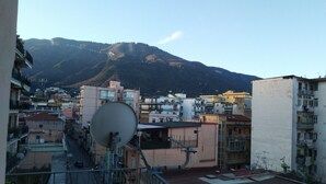Zona residencial con edificios, una antena parabólica y una montaña al fondo.