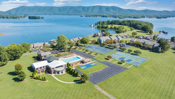 An aerial view of a residential area with a swimming pool, tennis courts, and a large lake in the background. - Loft Condo with Stunning Lake Views (Moneta)