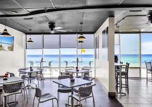 A restaurant with tables and chairs, large windows, and a view of the beach. - Tidewater Bliss 2012–Gulf Views–Sleeps 6 (Panama City Beach)