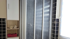 A bathroom with a glass shower enclosure, a white cabinet with a red towel, and black and white tiled walls. - Vacation apartment Huschenbett in a rural idyll (Nessetal)