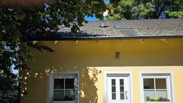 A yellow building with two windows and a door, a small porch, and a tiled roof. - Vacation apartment Huschenbett in a rural idyll (Nessetal)