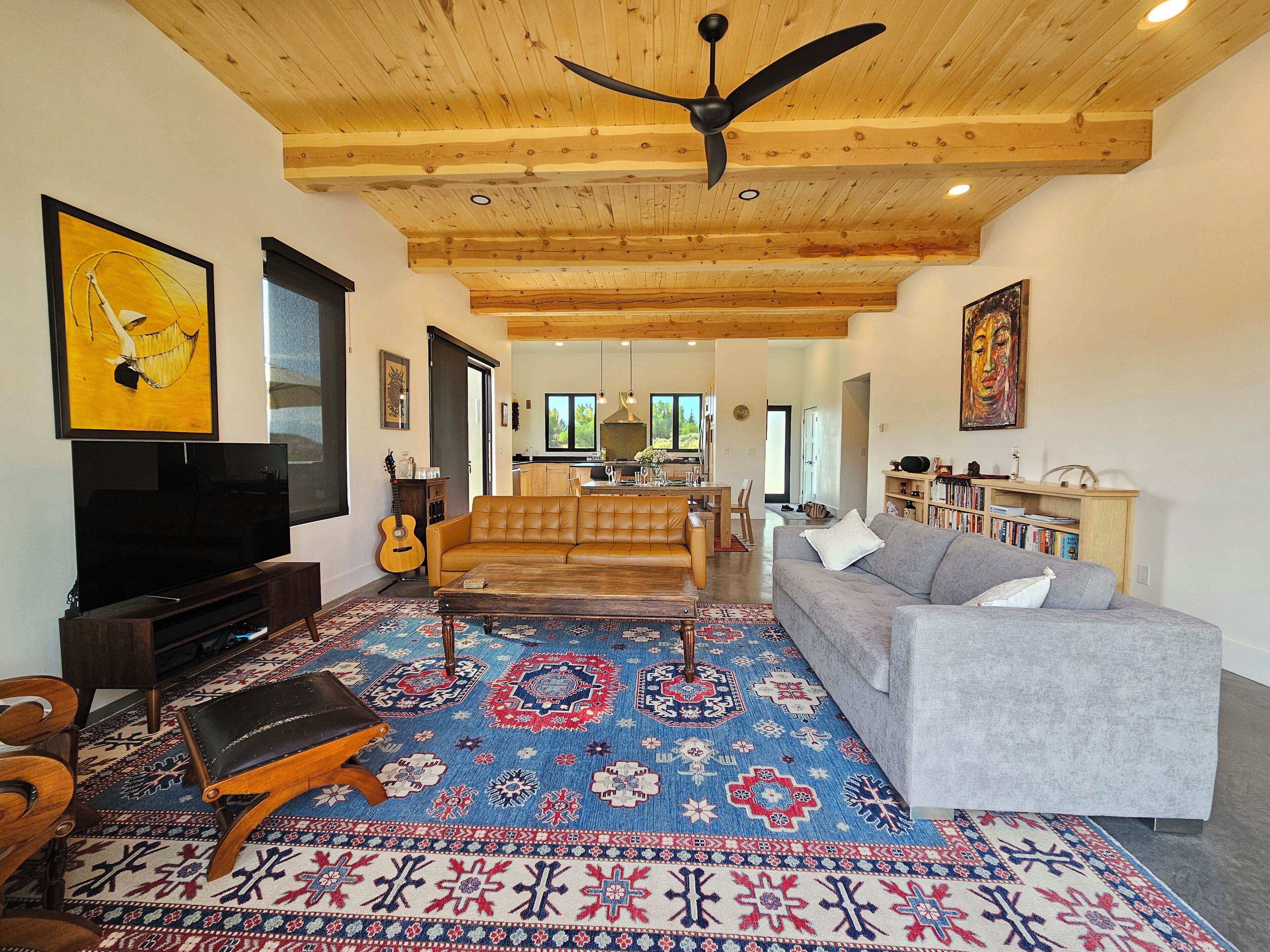 A spacious living room with a large TV, a sofa, a coffee table, and a patterned rug.