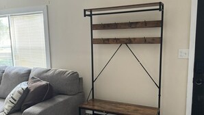 Un salon avec un canapé gris, une étagère en bois et une porte noire.