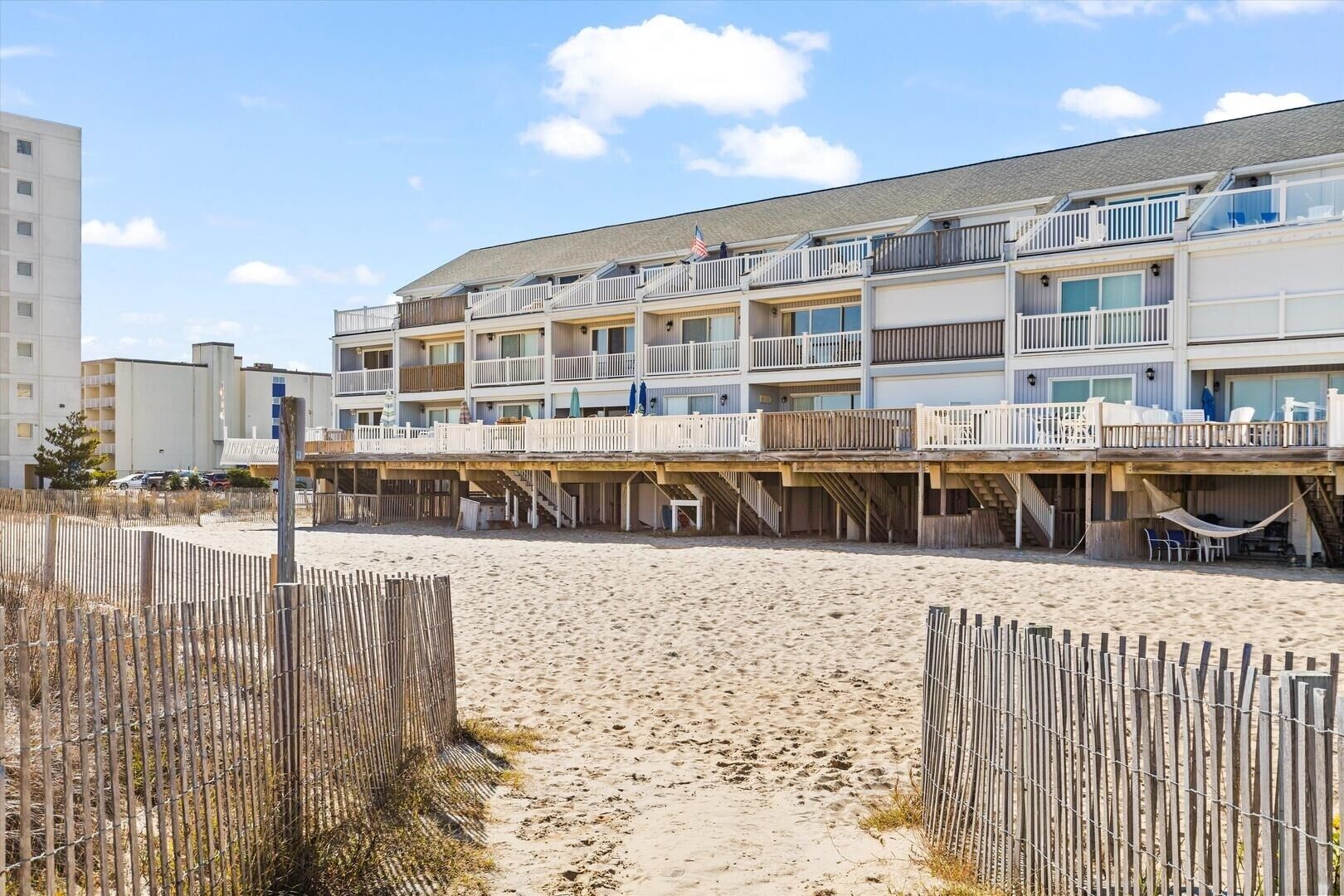 A beachfront hotel with multiple balconies and a sandy beach in the foreground.