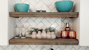 Une cuisine avec deux étagères en bois où sont disposés des objets décoratifs et des ustensiles de cuisine.