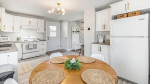 Une cuisine moderne avec des armoires blanches, un four encastré et un réfrigérateur. On y trouve une table à manger avec des sets de table et un centre de table.