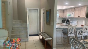 A spacious kitchen with modern appliances, a dining area with a bench, and a staircase leading to another level. - Bocilla Island Club Unit C-13 (Bokeelia)