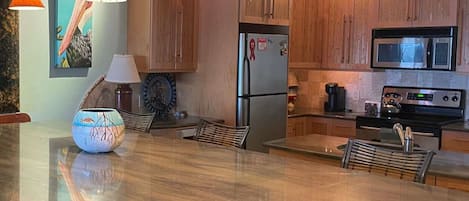 A modern kitchen with wooden cabinets, stainless steel appliances, and pendant lighting.